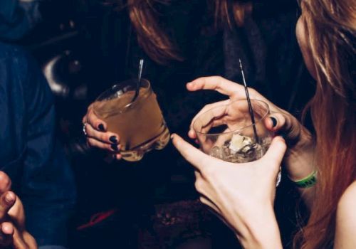 Three people socializing and laughing, each holding a drink with straws in hand.