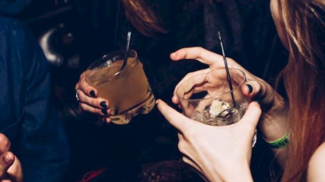 Three people socializing and laughing, each holding a drink with straws in hand.