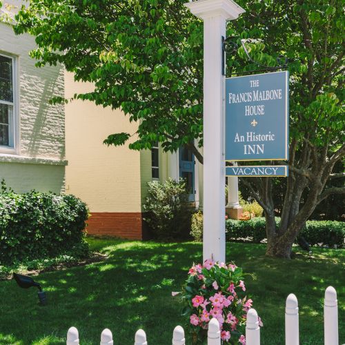 A quaint house with a white picket fence and sign reading 