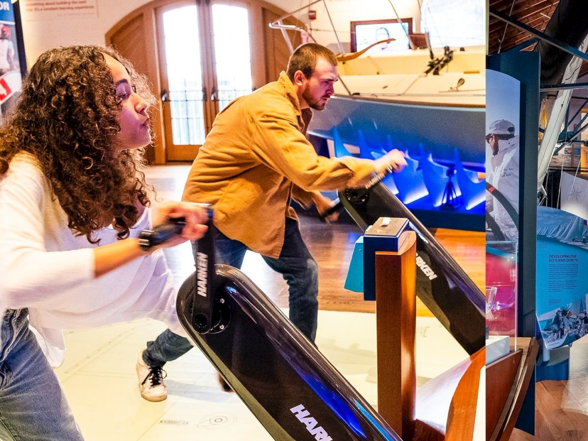 People in a workshop/exhibit try out a blue robotics display with a long track while others watch and test the controls.