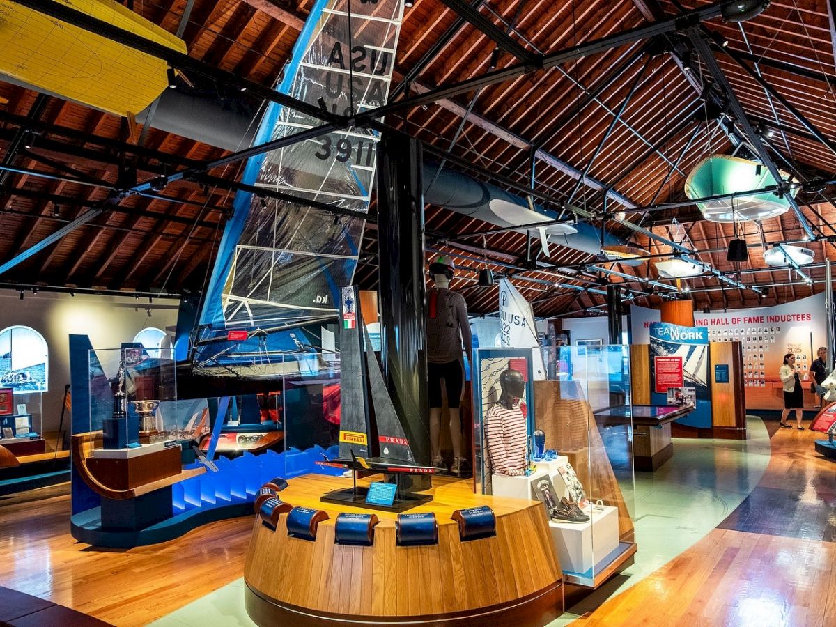 Inside a museum-style exhibit hall with display cases, glass sculptures, blue signage, and a mannequin under an arched ceiling.